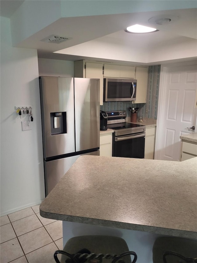 482 Pendleton Pl, Venice, FL 34292 - kitchen with appliances with stainless steel finishes, light tile patterned floors, tasteful backsplash, and a breakfast bar area
