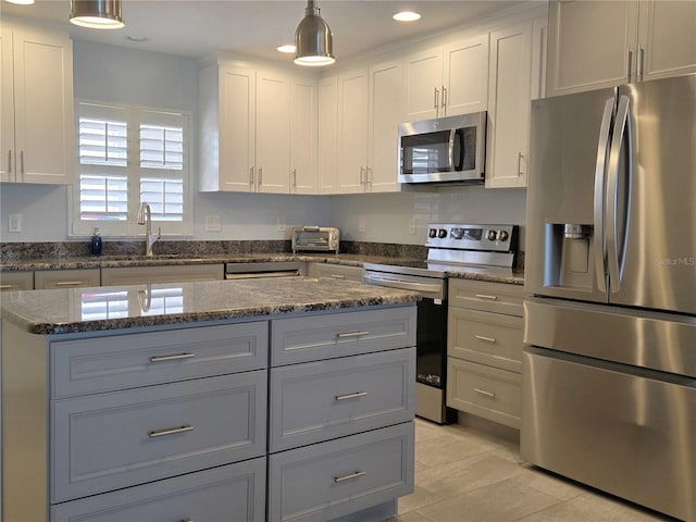 333 The Esplanade N Unit 102, Venice, FL 34285 - kitchen featuring appliances with stainless steel finishes, light tile patterned floors, gray cabinets, dark stone countertops, and a center island