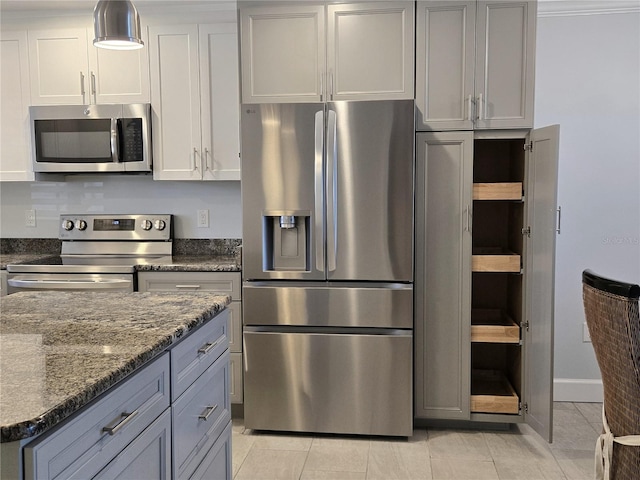 333 The Esplanade N Unit 102, Venice, FL 34285 - kitchen with stainless steel appliances, light tile patterned floors, dark stone counters, and gray cabinets