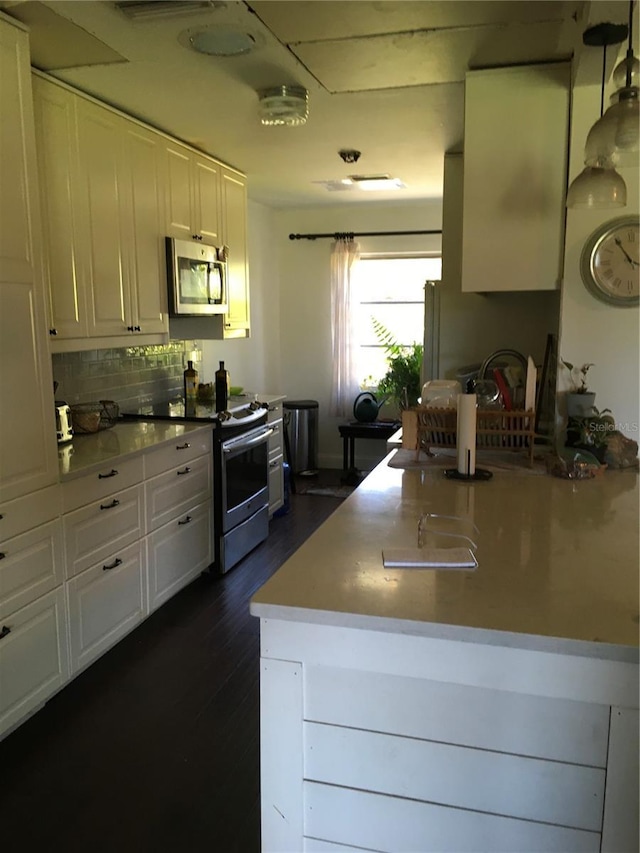 3661 Sterling Rd, Venice, FL 34293 - kitchen featuring appliances with stainless steel finishes, white cabinets, tasteful backsplash, dark wood finished floors, and a peninsula