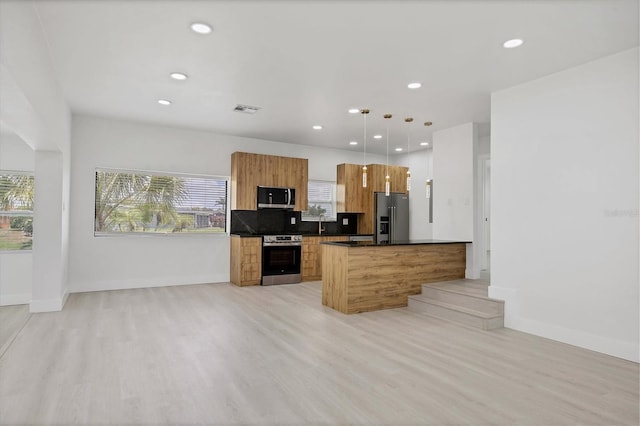 6821 Marius Rd, North Port, FL 34287 - kitchen featuring stainless steel appliances, brown cabinets, modern cabinets, dark countertops, and hanging light fixtures