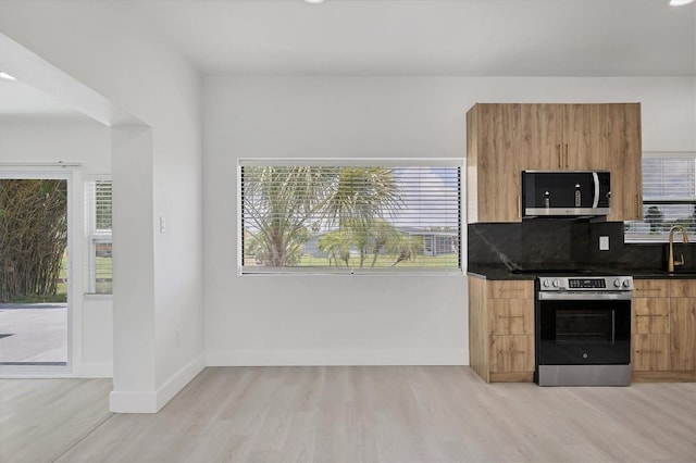 6821 Marius Rd, North Port, FL 34287 - kitchen featuring appliances with stainless steel finishes, light wood-style flooring, dark countertops, modern cabinets, and backsplash