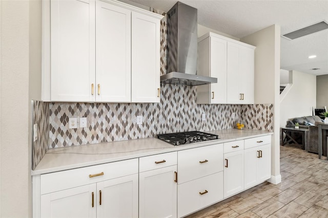 12617 Oak Hill Way, Parrish, FL 34219 - kitchen featuring wall chimney exhaust hood, stainless steel gas cooktop, white cabinetry, decorative backsplash, and light wood finished floors