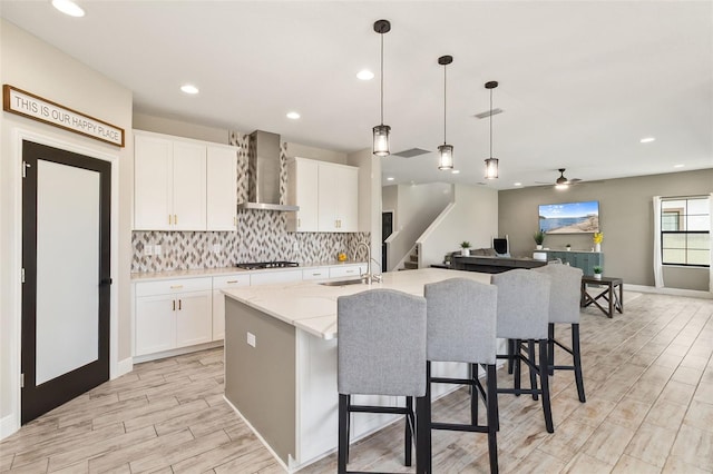 12617 Oak Hill Way, Parrish, FL 34219 - kitchen featuring wall chimney exhaust hood, tasteful backsplash, white cabinets, a ceiling fan, and an island with sink