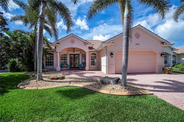 4308 Via Del Santi, Venice, FL 34293 - mediterranean / spanish home featuring french doors, an attached garage, stucco siding, a tile roof, and decorative driveway