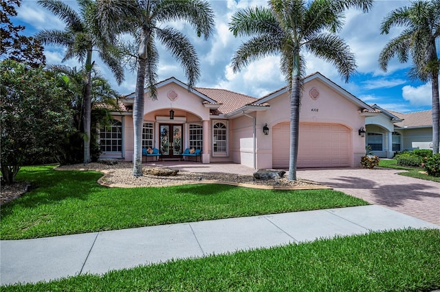 4308 Via Del Santi, Venice, FL 34293 - mediterranean / spanish home with french doors, stucco siding, an attached garage, a front lawn, and driveway