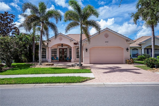 4308 Via Del Santi, Venice, FL 34293 - mediterranean / spanish-style house with french doors, stucco siding, a garage, a tiled roof, and driveway
