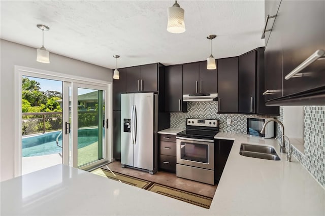 2555 Yucca Rd, Venice, FL 34293 - kitchen featuring appliances with stainless steel finishes, under cabinet range hood, backsplash, light countertops, and decorative light fixtures