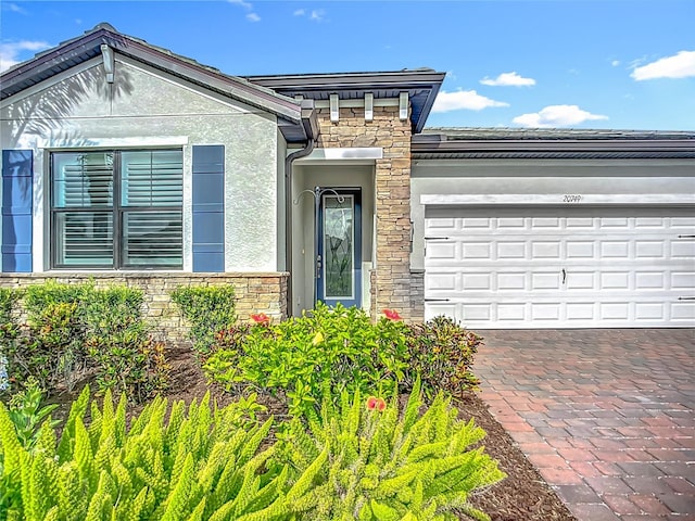 20749 Swallowtail Ct, Venice, FL 34293 - view of front facade with stucco siding, stone siding, a garage, and driveway