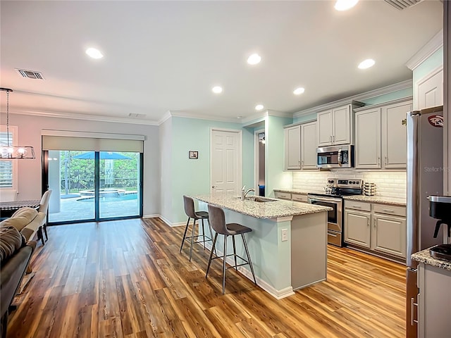 20749 Swallowtail Ct, Venice, FL 34293 - kitchen with stainless steel appliances, ornamental molding, wood finished floors, a breakfast bar area, and tasteful backsplash