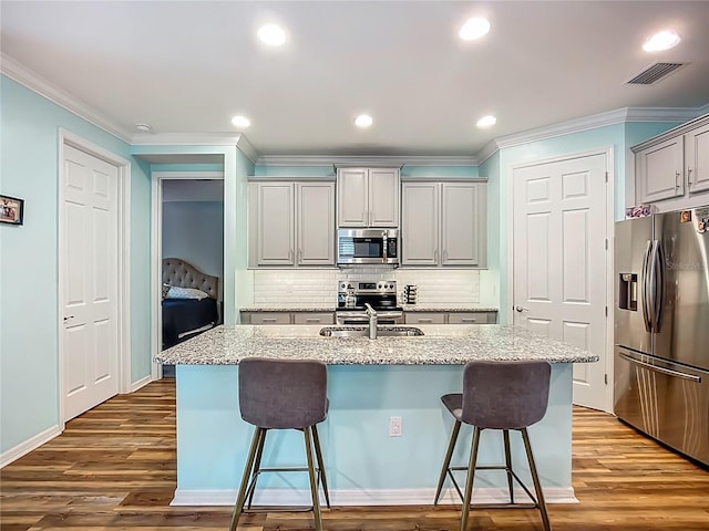 20749 Swallowtail Ct, Venice, FL 34293 - kitchen featuring appliances with stainless steel finishes, gray cabinets, ornamental molding, a breakfast bar area, and backsplash