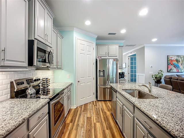 20749 Swallowtail Ct, Venice, FL 34293 - kitchen with appliances with stainless steel finishes, ornamental molding, gray cabinets, light wood finished floors, and backsplash