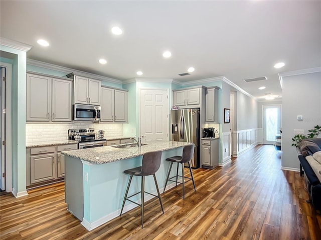 20749 Swallowtail Ct, Venice, FL 34293 - kitchen with appliances with stainless steel finishes, gray cabinets, ornamental molding, a kitchen breakfast bar, and dark wood-style flooring