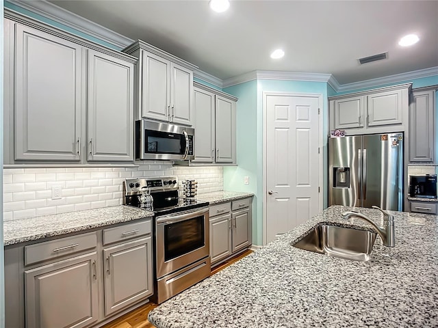20749 Swallowtail Ct, Venice, FL 34293 - kitchen featuring appliances with stainless steel finishes, gray cabinetry, crown molding, and light stone countertops