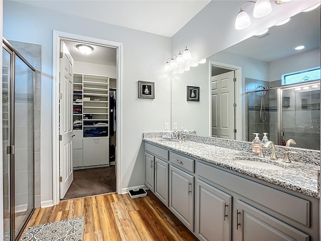 20749 Swallowtail Ct, Venice, FL 34293 - bathroom featuring wood finished floors, double vanity, a stall shower, and a spacious closet
