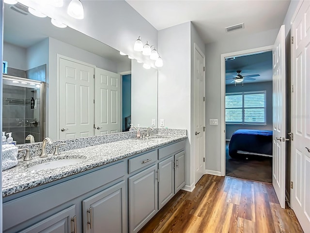 20749 Swallowtail Ct, Venice, FL 34293 - full bath with a ceiling fan, connected bathroom, double vanity, a shower stall, and wood finished floors