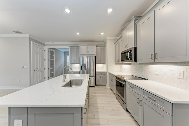 257 Teramo Way, Nokomis, FL 34275 - kitchen with gray cabinetry, appliances with stainless steel finishes, crown molding, light wood-type flooring, and decorative backsplash
