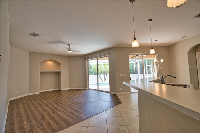 4150 Otoole St, North Port, FL 34291 - unfurnished living room with ceiling fan, arched walkways, built in features, light tile patterned floors, and a chandelier