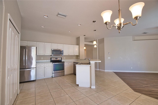 4150 Otoole St, North Port, FL 34291 - kitchen with appliances with stainless steel finishes, a peninsula, light tile patterned flooring, light countertops, and white cabinetry