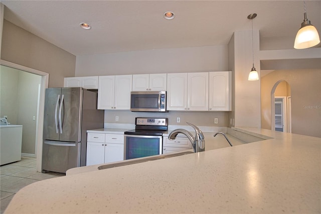 4150 Otoole St, North Port, FL 34291 - kitchen with appliances with stainless steel finishes, washer / dryer, arched walkways, white cabinetry, and light countertops