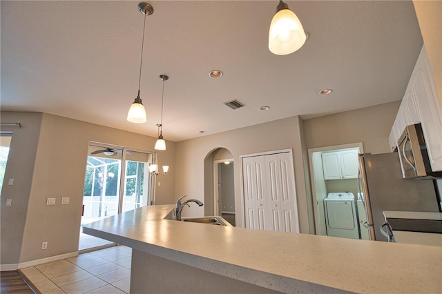 4150 Otoole St, North Port, FL 34291 - kitchen with washer / dryer, stainless steel microwave, arched walkways, white cabinets, and a peninsula
