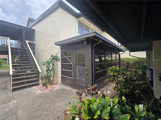 624 White Pine Tree Rd Unit 5, Venice, FL 34285 - view of side of property featuring stairway, stucco siding, and a sunroom