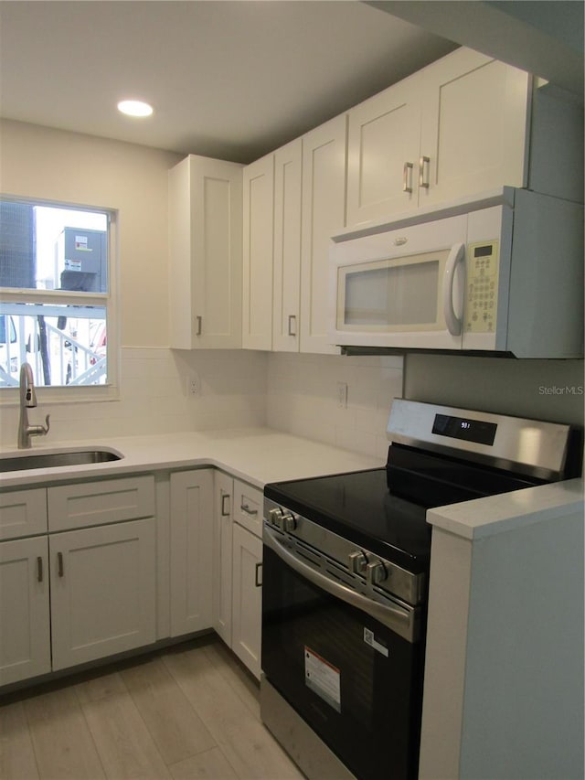 999 Inlet Cir Unit D101, Venice, FL 34285 - kitchen with stainless steel electric stove, white microwave, light wood finished floors, recessed lighting, and decorative backsplash