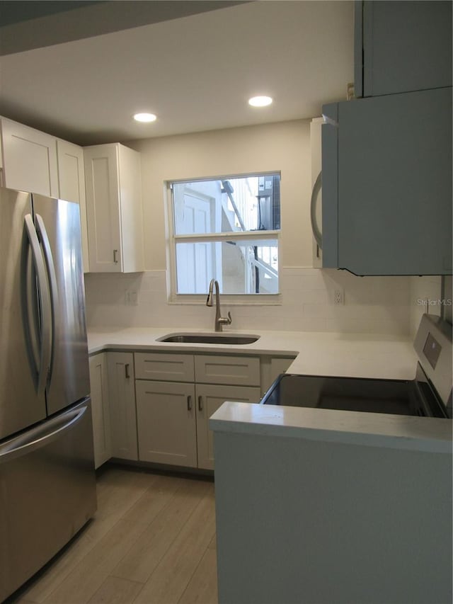 999 Inlet Cir Unit D101, Venice, FL 34285 - kitchen with freestanding refrigerator, white microwave, light wood-style floors, backsplash, and white cabinetry