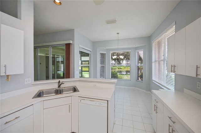 519 Catalina Isles Cir, Venice, FL 34292 - kitchen with dishwasher, a peninsula, light countertops, light tile patterned floors, and white cabinets