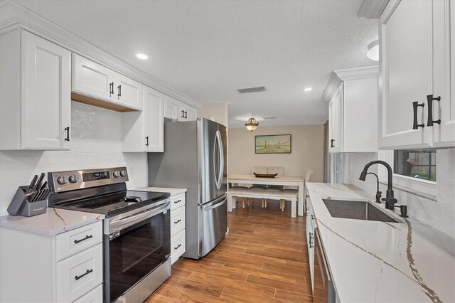 386 Nightingale Rd, Venice, FL 34293 - kitchen featuring appliances with stainless steel finishes, white cabinetry, backsplash, light wood finished floors, and recessed lighting