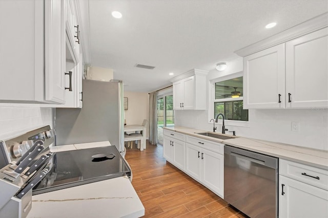 386 Nightingale Rd, Venice, FL 34293 - kitchen with appliances with stainless steel finishes, light wood-style flooring, white cabinets, recessed lighting, and backsplash