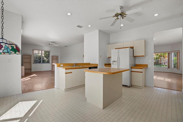 9528 Knightsbridge Cir, Sarasota, FL 34238 - kitchen with white refrigerator with ice dispenser, ceiling fan, open floor plan, a kitchen island, and light countertops