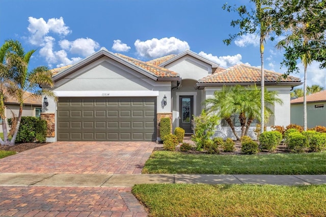 13334 Pacchio St, Venice, FL 34293 - mediterranean / spanish home featuring a garage, decorative driveway, a tile roof, stucco siding, and a front lawn