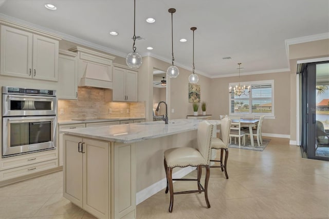 13334 Pacchio St, Venice, FL 34293 - kitchen with double oven, premium range hood, decorative backsplash, light stone counters, and a kitchen bar