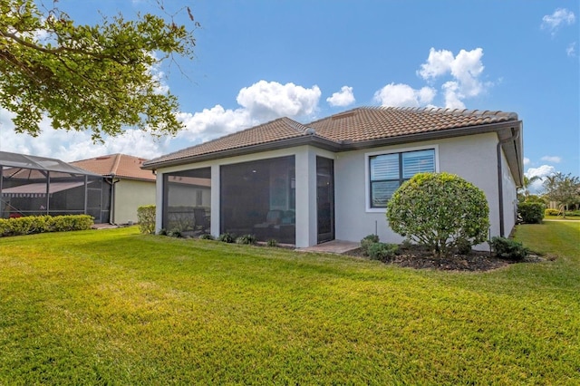 13334 Pacchio St, Venice, FL 34293 - rear view of property featuring a tiled roof, a lawn, stucco siding, and a sunroom