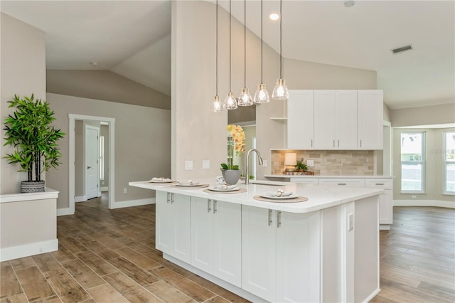 26115 Rampart Blvd, Punta Gorda, FL 33983 - kitchen featuring vaulted ceiling, light countertops, light wood-type flooring, and white cabinets