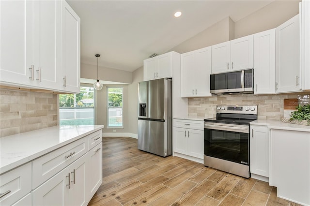 26115 Rampart Blvd, Punta Gorda, FL 33983 - kitchen with appliances with stainless steel finishes, vaulted ceiling, white cabinetry, backsplash, and light wood finished floors