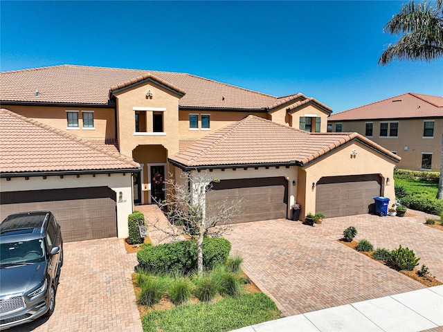 23527 Awabuki Unit 202, Venice, FL 34293 - view of front of house with stucco siding, decorative driveway, a tiled roof, and an attached garage
