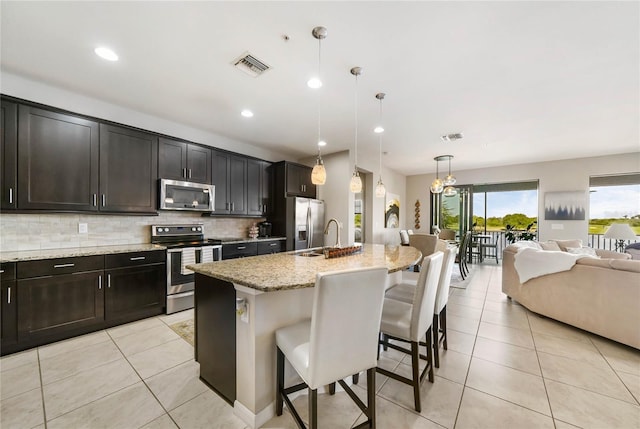 23527 Awabuki Unit 202, Venice, FL 34293 - kitchen with stainless steel appliances, light tile patterned floors, a kitchen bar, open floor plan, and tasteful backsplash
