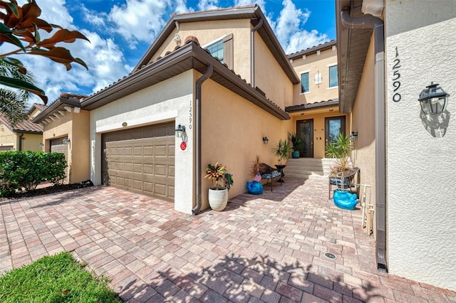 12590 Ghiberti Cir Unit 201, Venice, FL 34293 - view of front of house with stucco siding, an attached garage, and decorative driveway