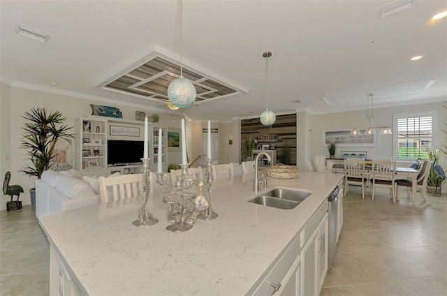 12590 Ghiberti Cir Unit 201, Venice, FL 34293 - kitchen featuring a kitchen island with sink, white cabinets, open floor plan, light stone countertops, and ornamental molding