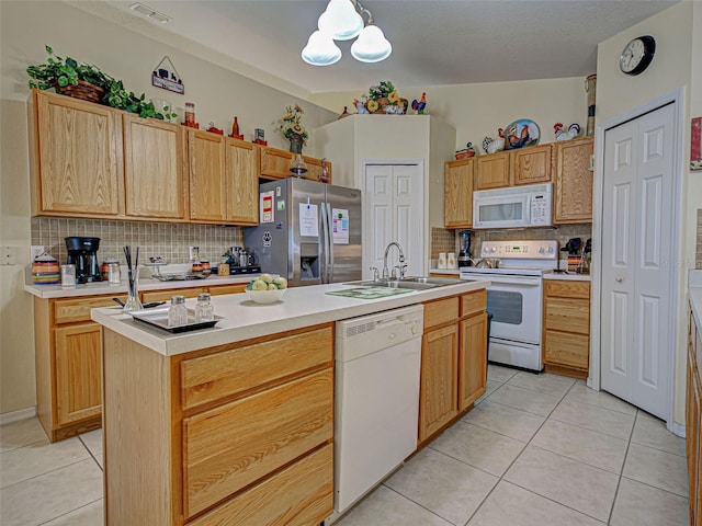 3139 Point St, North Port, FL 34286 - kitchen with white appliances, tasteful backsplash, light tile patterned floors, light countertops, and a kitchen island with sink