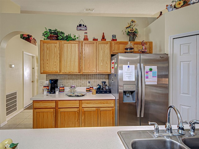 3139 Point St, North Port, FL 34286 - kitchen featuring stainless steel fridge with ice dispenser, light tile patterned floors, tasteful backsplash, light countertops, and arched walkways