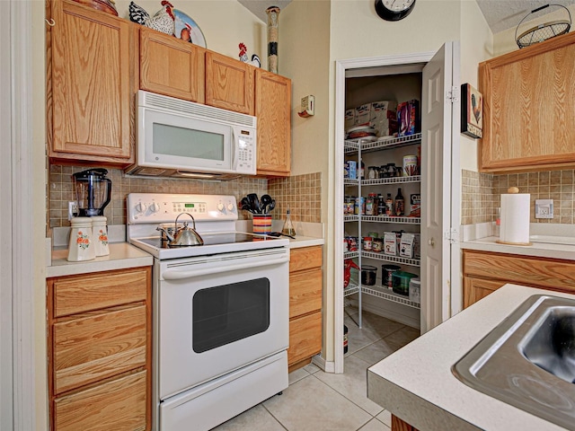 3139 Point St, North Port, FL 34286 - kitchen with white appliances, tasteful backsplash, light tile patterned flooring, and light countertops