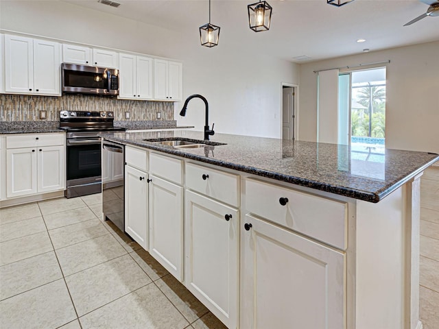 9157 Genesee St, Port Charlotte, FL 33981 - kitchen featuring stainless steel appliances, tasteful backsplash, dark stone countertops, a center island with sink, and white cabinetry