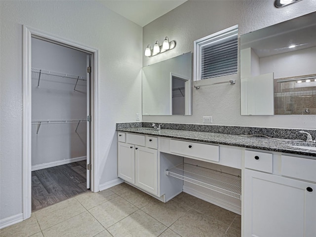 9157 Genesee St, Port Charlotte, FL 33981 - bathroom featuring double vanity, tiled shower, a textured wall, a spacious closet, and tile patterned flooring