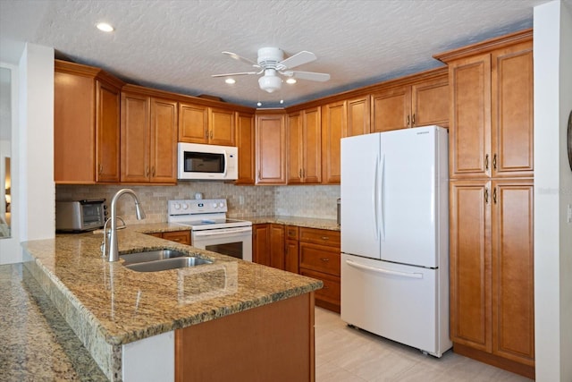 2941 Datura Rd, Venice, FL 34293 - kitchen with white appliances, brown cabinetry, a peninsula, light stone countertops, and recessed lighting