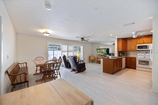 2941 Datura Rd, Venice, FL 34293 - kitchen featuring white appliances, ceiling fan, a peninsula, open floor plan, and brown cabinets