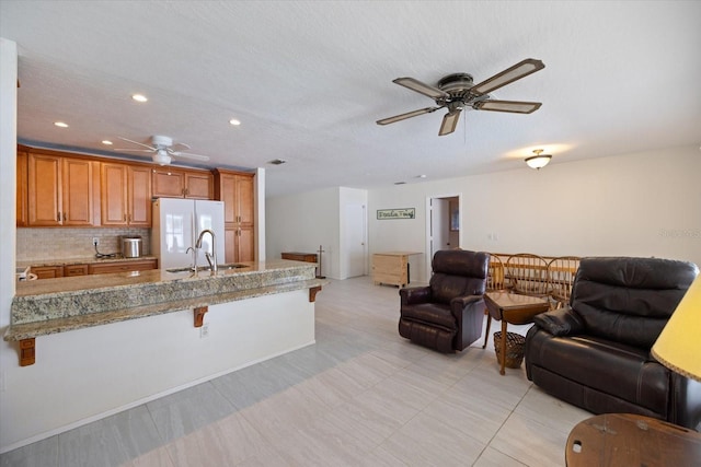 2941 Datura Rd, Venice, FL 34293 - kitchen with a ceiling fan, freestanding refrigerator, open floor plan, a kitchen breakfast bar, and a peninsula