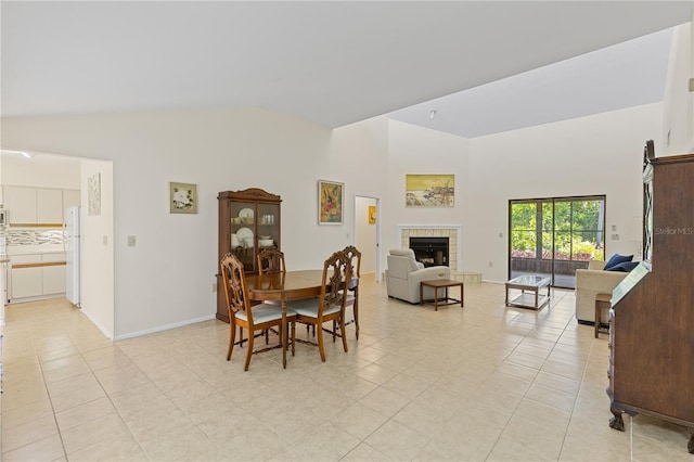 1315 Pine Needle Rd, Venice, FL 34285 - dining area featuring light tile patterned floors, high vaulted ceiling, and a tiled fireplace